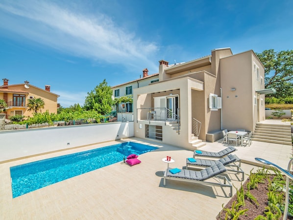 Relax by the pool in a spacious outdoor area with lounge chairs and a table.