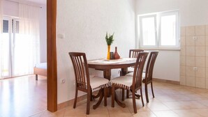 A dining area with a round wooden table, four chairs, and a vase with a plant. - Charming Seaside Apartment (Omis)