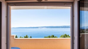 A balcony with a view of the sea, a table, and a chair. - Charming Seaside Apartment (Omis)