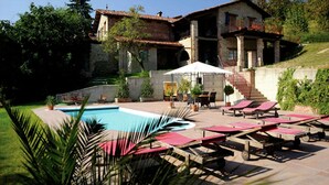 Una villa con piscina, mobiliario de exterior y una escalera que conduce al piso superior.