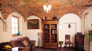 Una habitación acogedora con techo de ladrillo, una estantería de madera, un sofá de cuero y una estufa antigua.