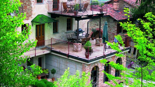 Un edificio de varios pisos con balcones, zona de estar al aire libre y jardín.