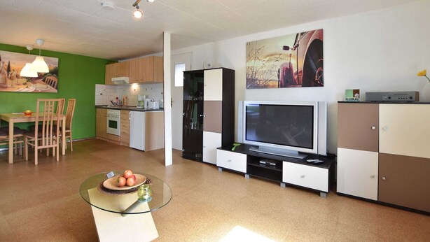 Una cocina moderna con comedor, una mesa de centro de vidrio y un televisor de pantalla plana.