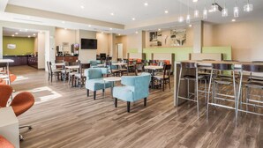 A spacious hotel lobby with multiple seating areas, a bar, and a kitchenette in the background. - Sleep Inn & Suites Park City - Wichita North (Wichita)