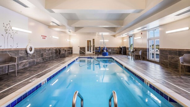 An indoor swimming pool with clear lane markings, a lifeguard chair, and a view of the outside through large windows. - Sleep Inn & Suites Park City - Wichita North (Wichita)