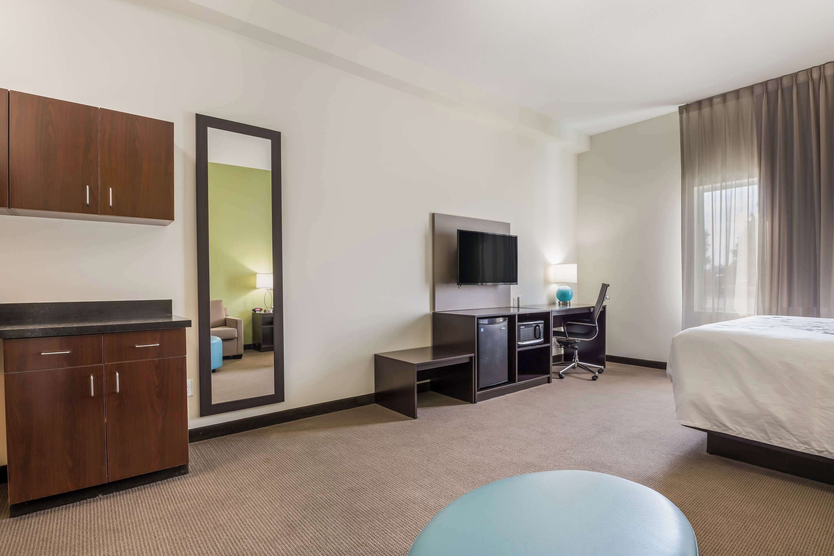 Une chambre d’hôtel comprenant un lit, un bureau avec un ordinateur, une télévision, une armoire et un miroir.