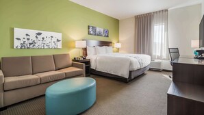 A hotel room with a bed, a sofa, a desk, and a large window with curtains. - Sleep Inn & Suites Park City - Wichita North (Wichita)