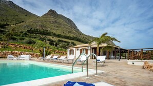 A poolside area with lounge chairs and a building in the background. - Splendid Holiday Home in Castellammare del Golfo near Beach (Castellammare del Golfo)