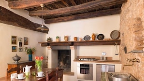 A rustic kitchen with exposed wooden beams, a gas stove, an oven, and a sink with a vintage faucet. - Scenic Stay in Spoleto (Spoleto)