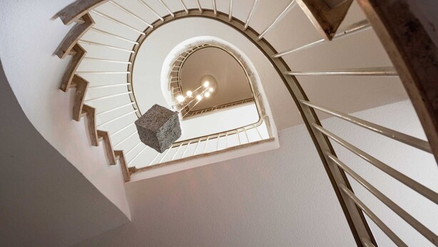 En spiraltrappa med en dekorativ detalj i sten och en lampa högst upp.