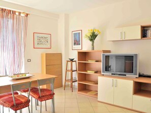 A compact living space with a dining area, a television, and a bookshelf.