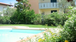 Una piscina rodeada de abundante vegetación y un edificio con balcones.