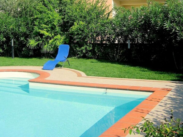 A swimming pool with a blue lounge chair and a tiled edge.