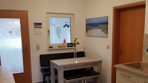 Eine kleine Küche mit Esstisch, einem Fenster mit Blick und einem Bild an der Wand.
