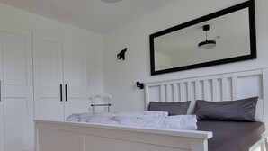 Ein Schlafzimmer mit einem Bett, einem weißen Kleiderschrank und einem großen Spiegel.