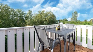 Um terraço com mesa e cadeiras, uma garrafa de vinho e uma taça.