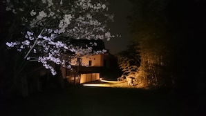 A house with a lit entrance and a cherry blossom tree in the foreground.