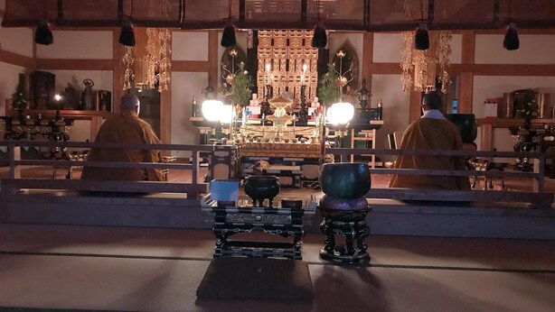 A traditional Japanese room with tatami flooring, a low table with a tea set, and a shoji screen in the background.