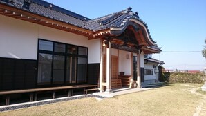 A traditional Japanese building with a tiled roof, large windows, and a wooden bench outside.