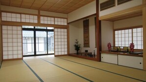 A traditional Japanese room with tatami flooring, sliding doors, and a low wooden desk with items on it.