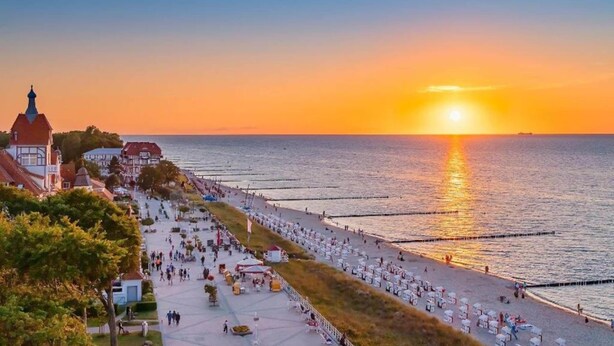 Un paseo marítimo con edificios y un atardecer sobre el mar.