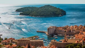 Una cittadina costiera con un'antica fortezza, una piccola isola e un porto turistico con imbarcazioni.