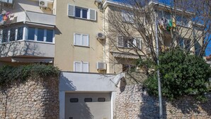 Un edificio residenziale a più piani con facciata in pietra, diverse finestre con persiane e un ingresso per garage.