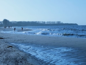 A beach with people walking along the shore.