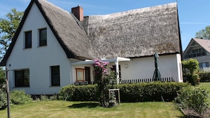 A traditional house with a steeply pitched thatched roof, white walls, and a small porch with a flower box. - Apartment in Pepelow for Zwei Personen (Am Salzhaff)