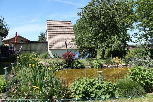 Ein Garten mit Teich, einem Hochhaus und einem Baum.