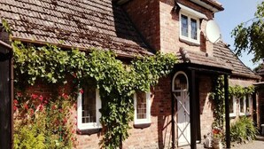 A traditional brick house with a sloped roof, ivy-covered walls, and a satellite dish. - Apartment in a Stylish House in the Countryside Near the Sea (Darlowo)