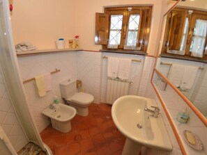 A bathroom with a toilet, bidet, and sink. There is a window with curtains and a towel rack above the sink. - Capannori Playful Cottage (Capannori)