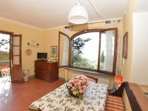 A room with a dining table, a TV, and a window with curtains. - Capannori Playful Cottage (Capannori)