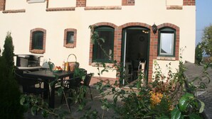 A two-story building with a brick facade and multiple windows. There is a patio area with a table and chairs. - Country House Near Baltic Sea Beach (Bastorf)
