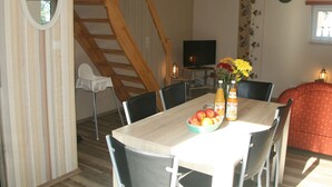 A dining area with a wooden staircase, a TV, and a clock on the wall. - Country House Near Baltic Sea Beach (Bastorf)