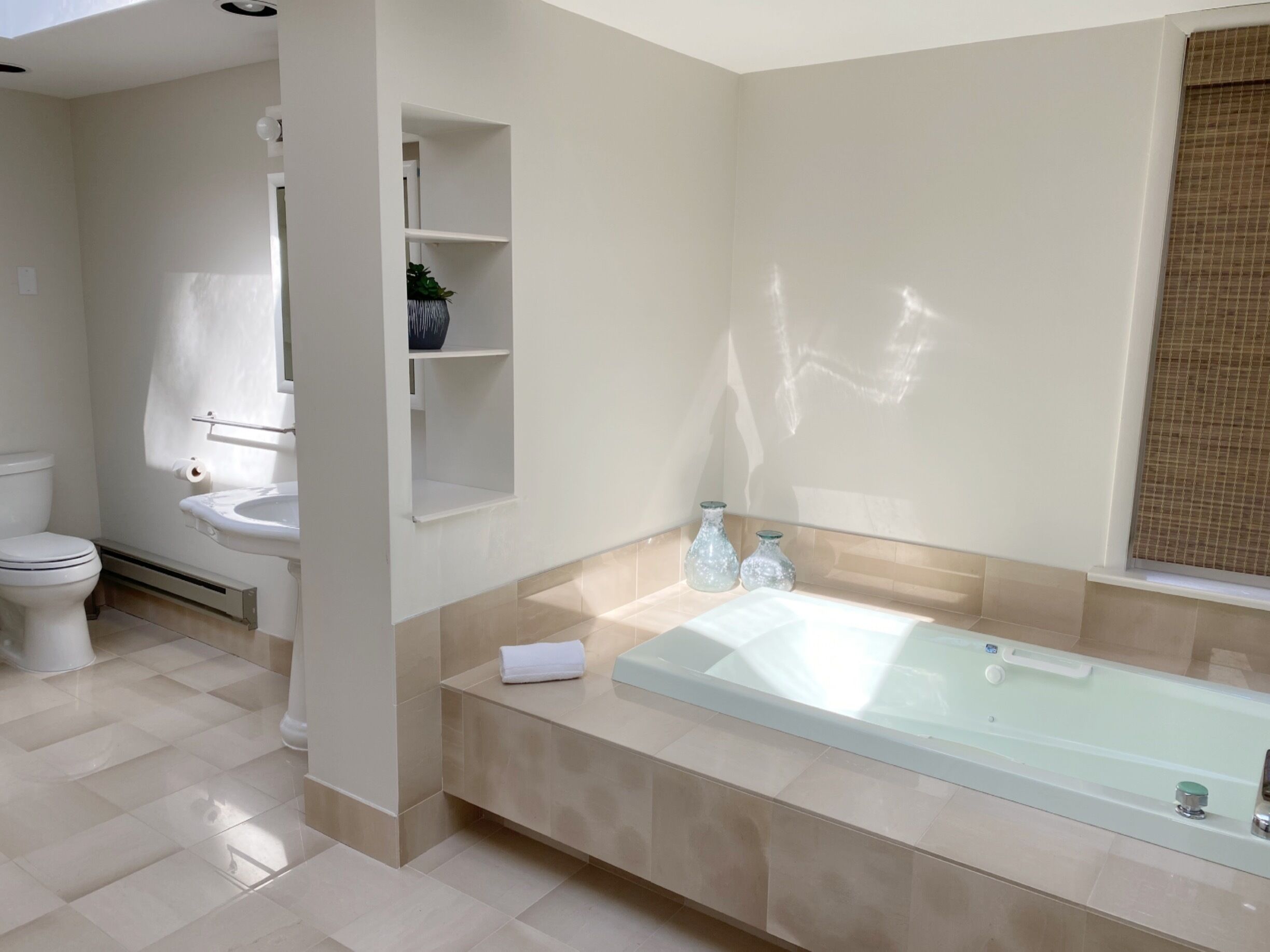 Une salle de bain moderne avec une baignoire entourée de parois en verre, des toilettes et un lavabo.