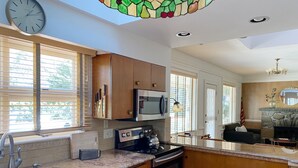 A modern kitchen with wooden cabinets, stainless steel appliances, and a large window. - 🌲🚣‍♂️🦅 Spacious Lake Cottage MSTR Suite LRG Deck Lake Wallenpaupack (Greentown)