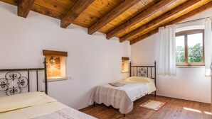 A bedroom with two beds, wooden beams, a window with curtains, and a small window with a light fixture. - Elegant Villa in Istria With Outdoor Pool (Tinjan)