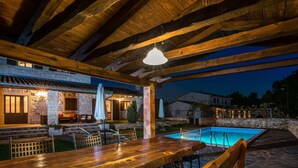An outdoor dining area with a pool, stone walls, and wooden beams. - Elegant Villa in Istria With Outdoor Pool (Tinjan)