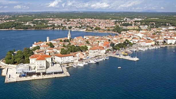 An aerial view of a coastal town with a marina, buildings with red roofs, and a prominent tower. - Elegant Villa in Istria With Outdoor Pool (Tinjan)