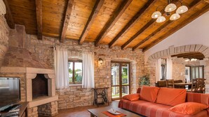 A rustic interior with a stone fireplace, wooden beams, a sofa, and a television. - Elegant Villa in Istria With Outdoor Pool (Tinjan)