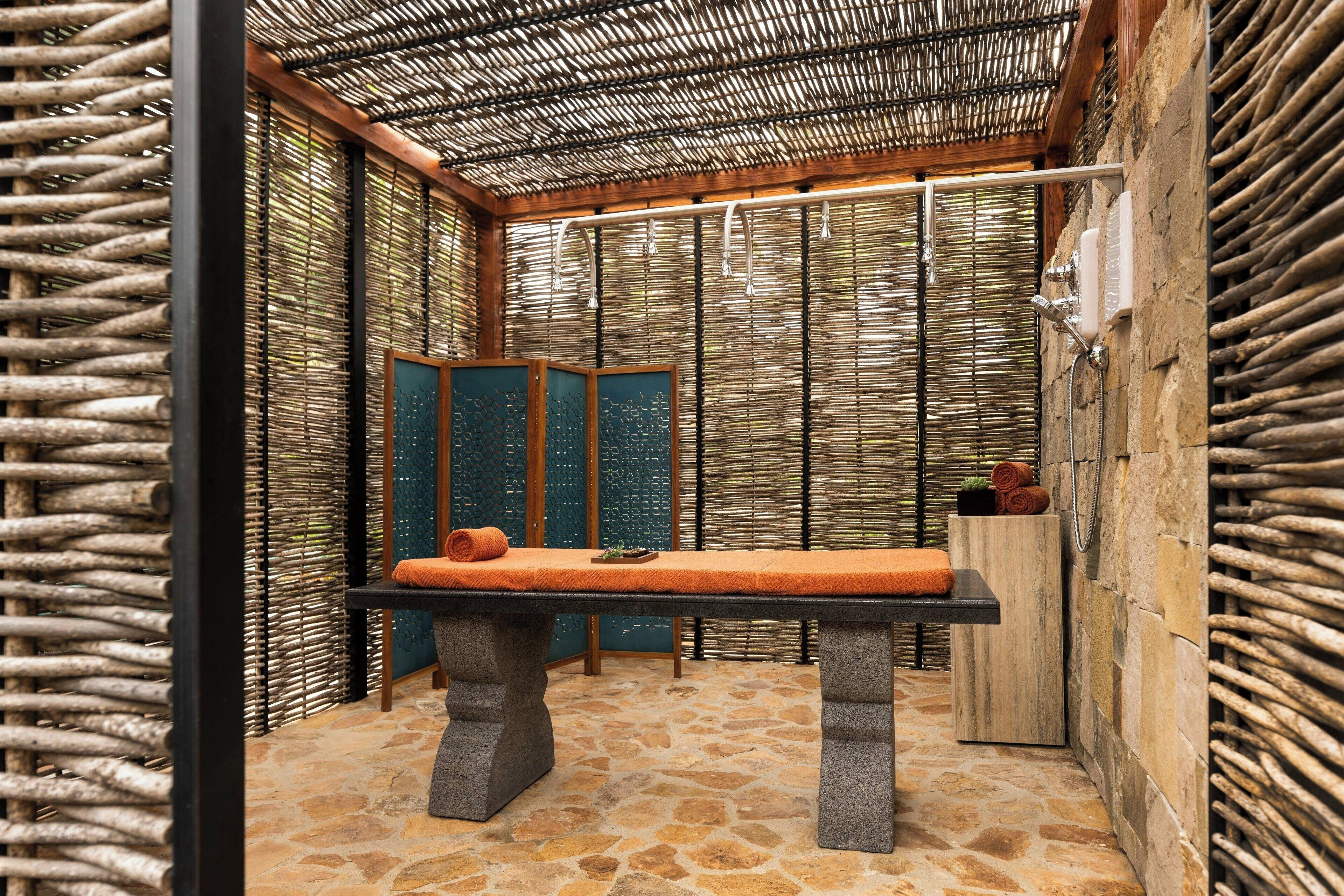 A room with a stone floor, a massage table, and a wooden cabinet.
