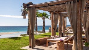 A beachside lounge with a thatched roof, cushioned seating, and a view of the ocean. - Zadun Los Cabos, a Ritz-Carlton Reserve Residence (San José del Cabo)