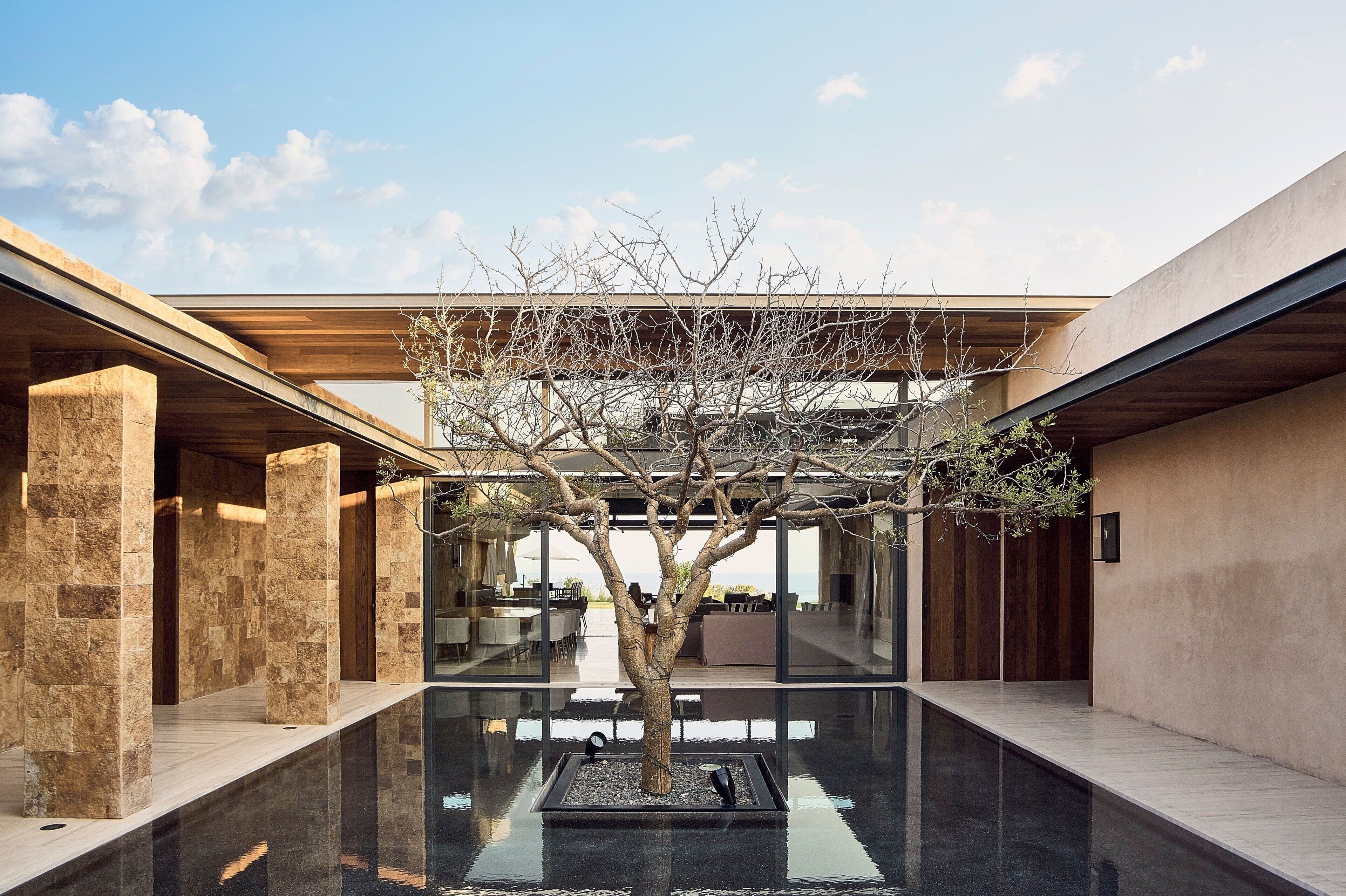 A modern building with a central courtyard featuring a tree and a reflective pool.