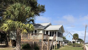 A two-story house with a wooden deck and a fenced yard. - Our Little Piece of Heaven (Edisto Island)