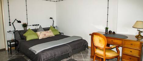 A bedroom with a bed, desk, chair, and two lamps.