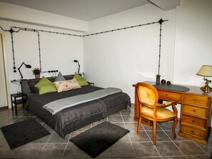 A bedroom with a bed, desk, chair, and two lamps.