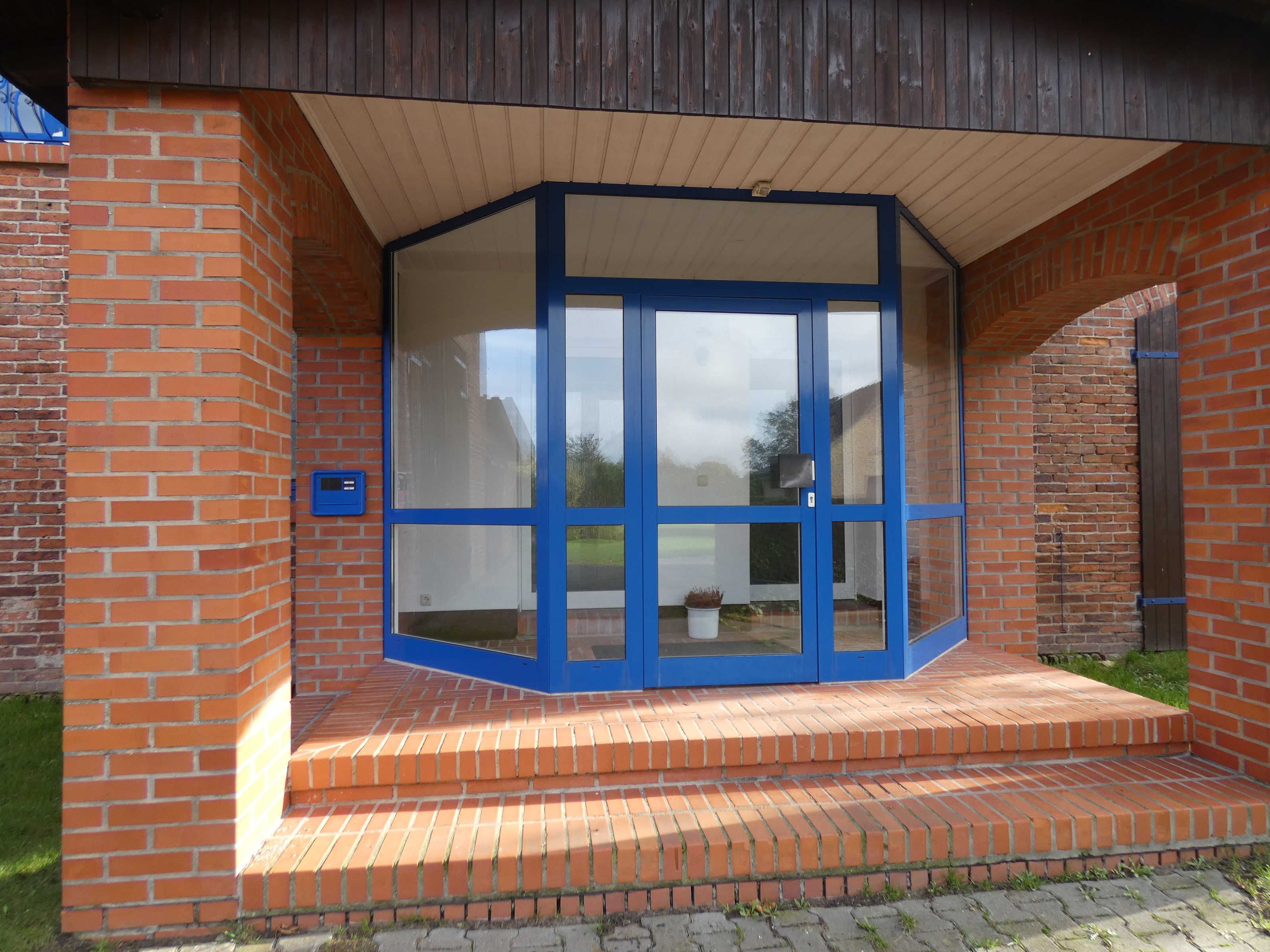 A building entrance with a glass door and brick walls.
