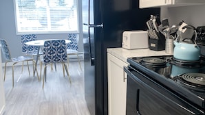 A modern kitchen with a black refrigerator, white cabinets, and a blue kettle on the stove. - Stylish, New & Clean 1b apt w/ King Bed+Pool+Gym+Parking (Beaverton)