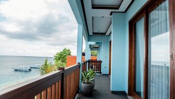 Un balcone con vista sul mare e sulle barche, una pianta in vaso e una ringhiera in legno.